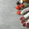 Сoncept of tasty food with salami sausage on gray textured background